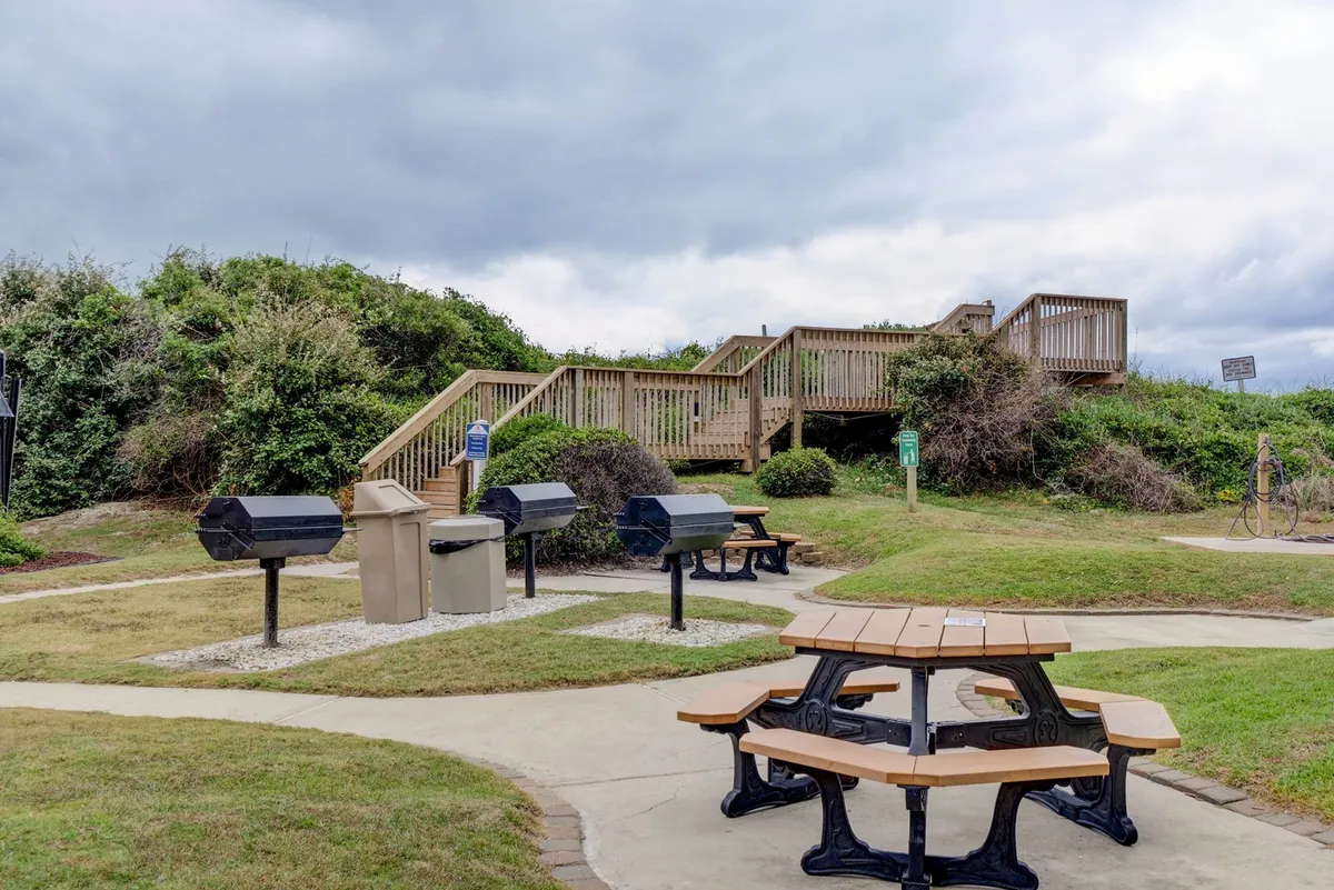 An inviting grilling and picnic area with wooden picnic tables and barbecue grills, set amid a relaxed outdoor space. The setting encourages communal meals, sunset barbecues, and spontaneous gatherings with friends and family.