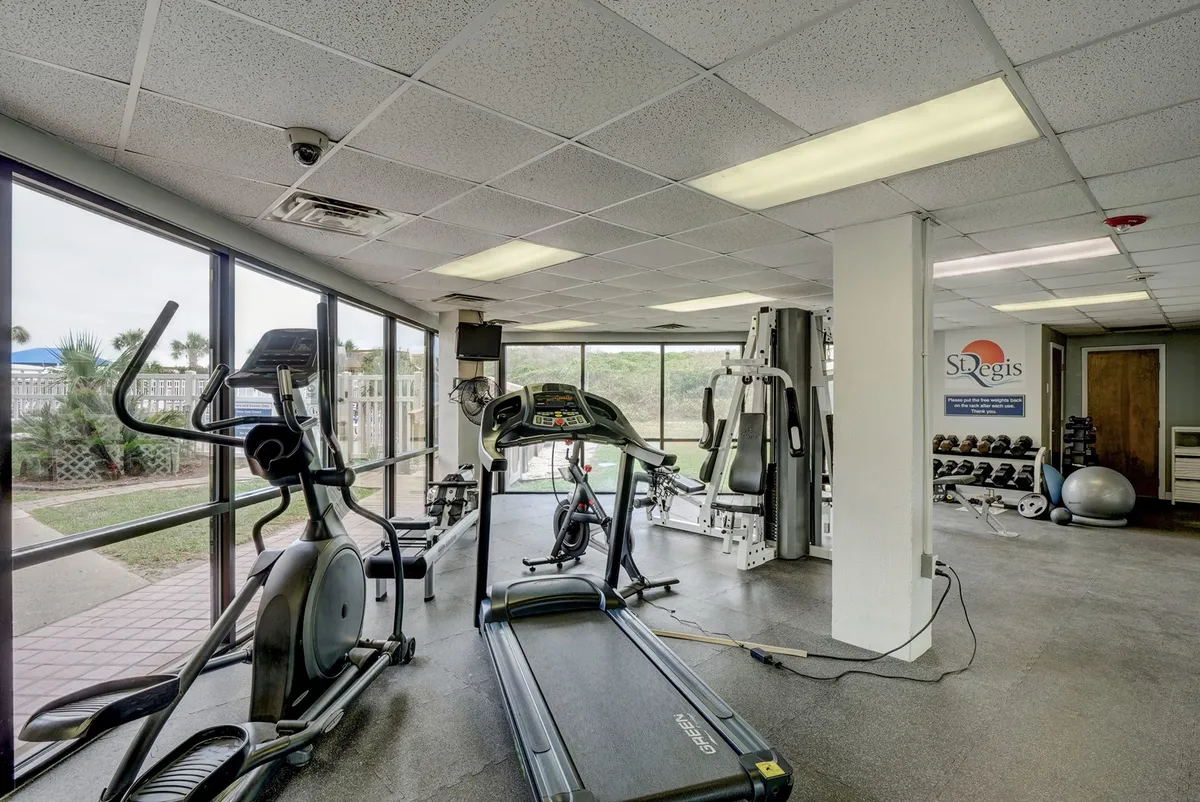 A bright, invigorating fitness center with treadmills, an elliptical, weight training equipment, and large windows that let in natural light. The view gives a sense of an energizing environment ideal for workouts and group fitness classes.